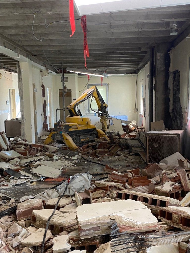 The BROKK® remote-controlled machine working in a gutted room full of brick and tile debris